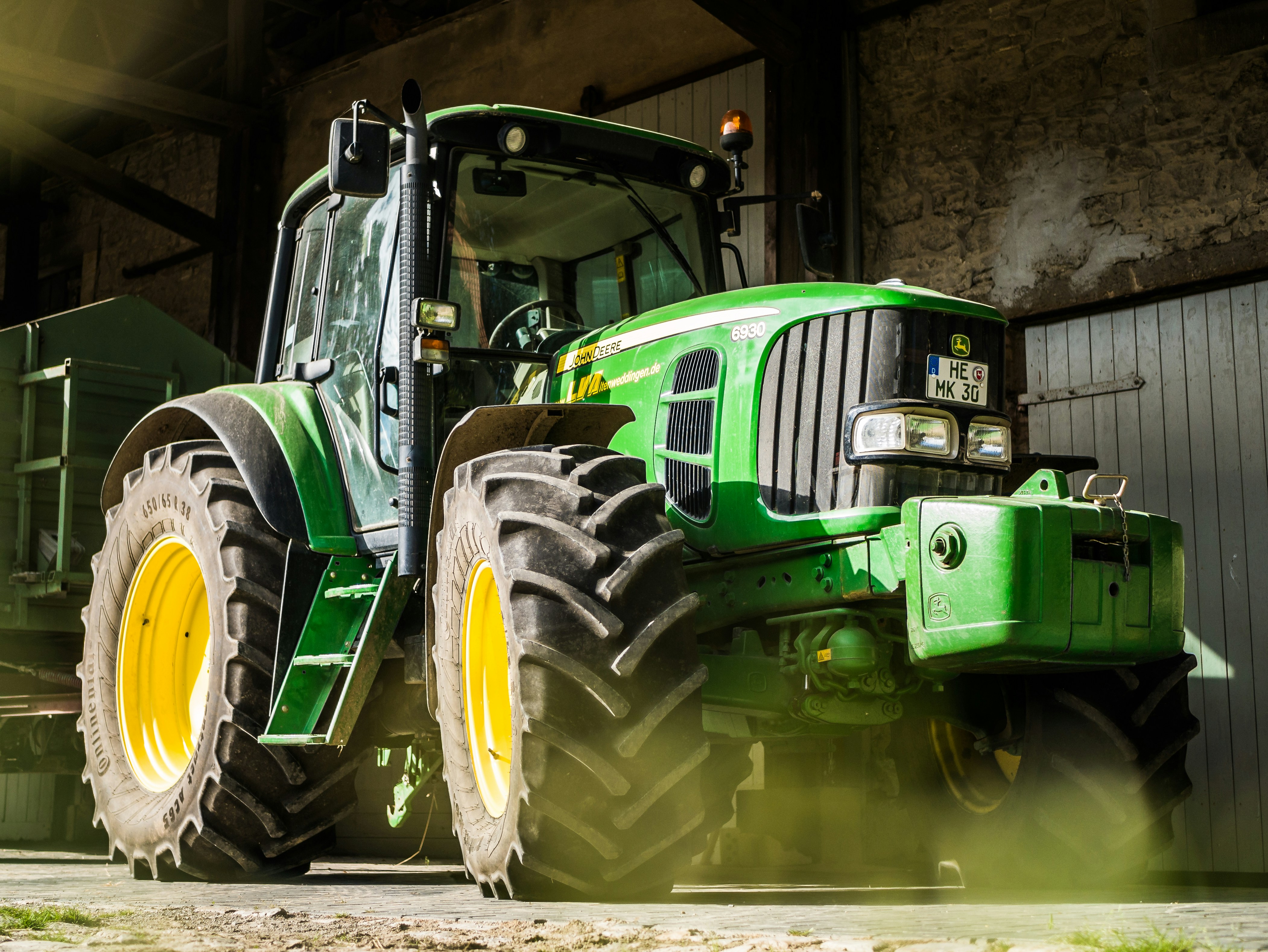 A tractor parked inside a barn, bathing in the sun
