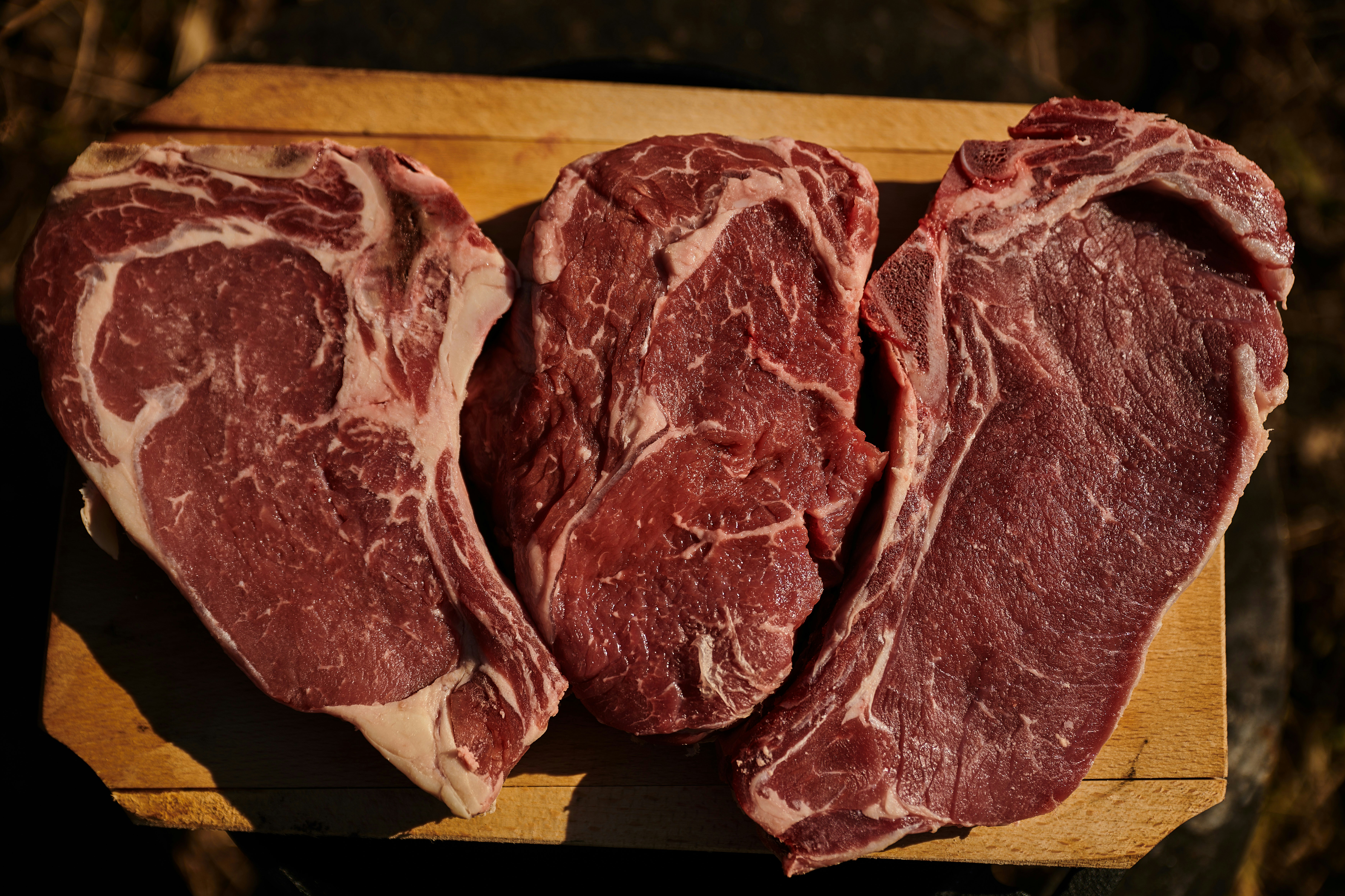 Three beef steaks on a chopping board